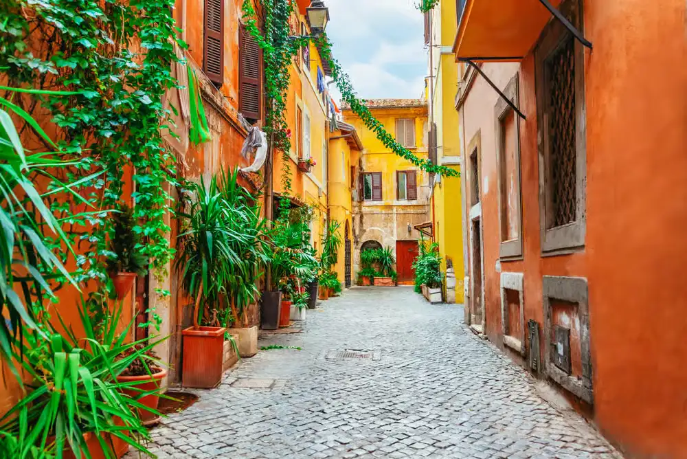 5. Explore the Quiet Streets of Trastevere
Trastevere’s narrow cobblestone lanes are lined with warm terracotta buildings, green vines, and potted plants. These quieter corners show the neighborhood’s local character away from its busiest squares.Visit in the morning when the streets feel calm and easy to explore. Walk slowly, notice the old doorways, and stop at a small café before the afternoon crowds arrive.