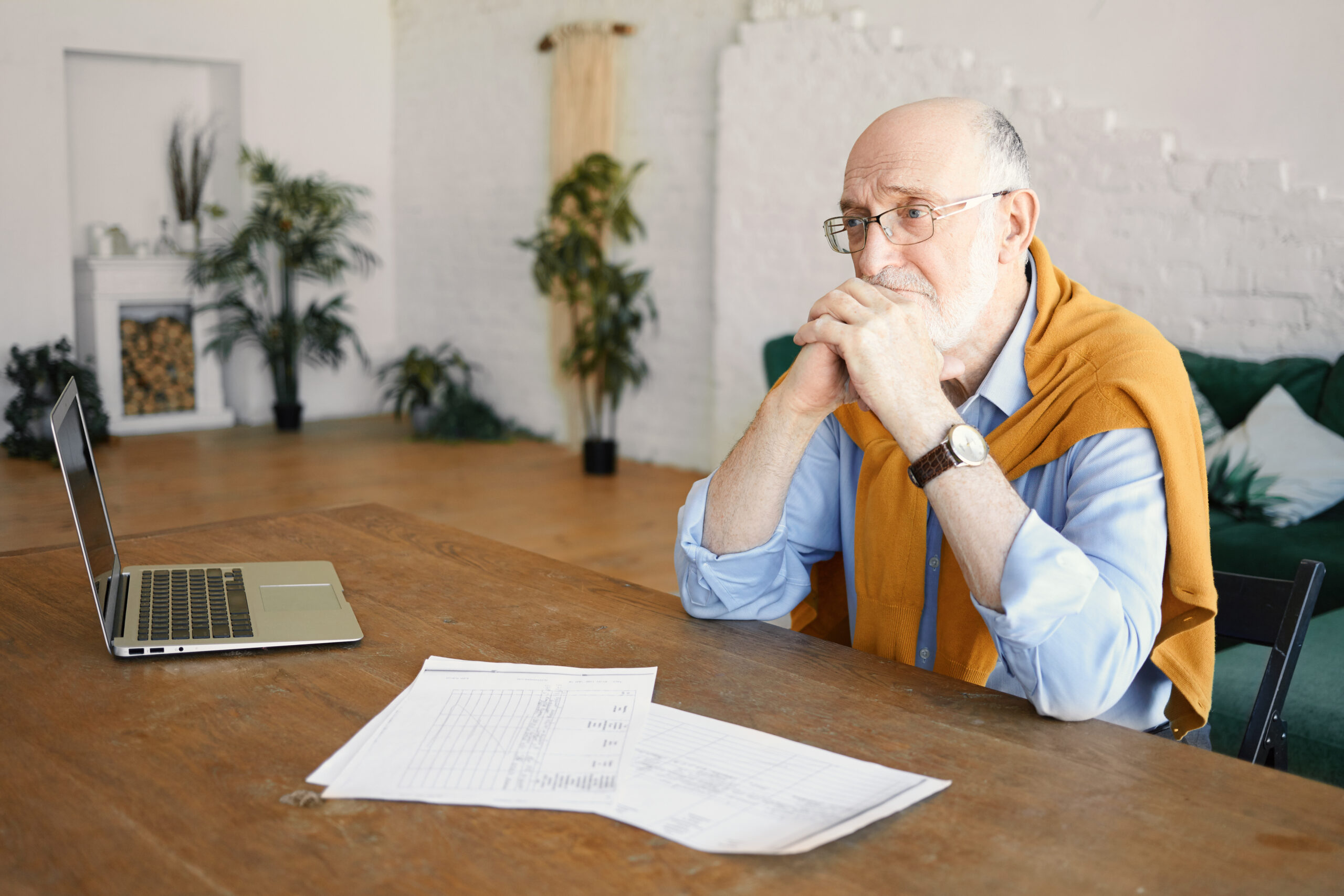 Indoor shot of unhappy sad senior bearded male entrepreneur sitt How Moving Slower Cuts Your Expenses in Half