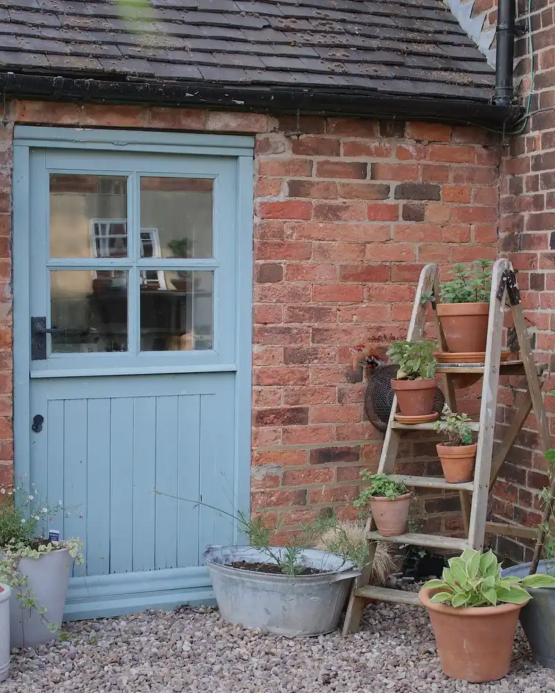 Rustic Ladder Display Beside A Cottage Door