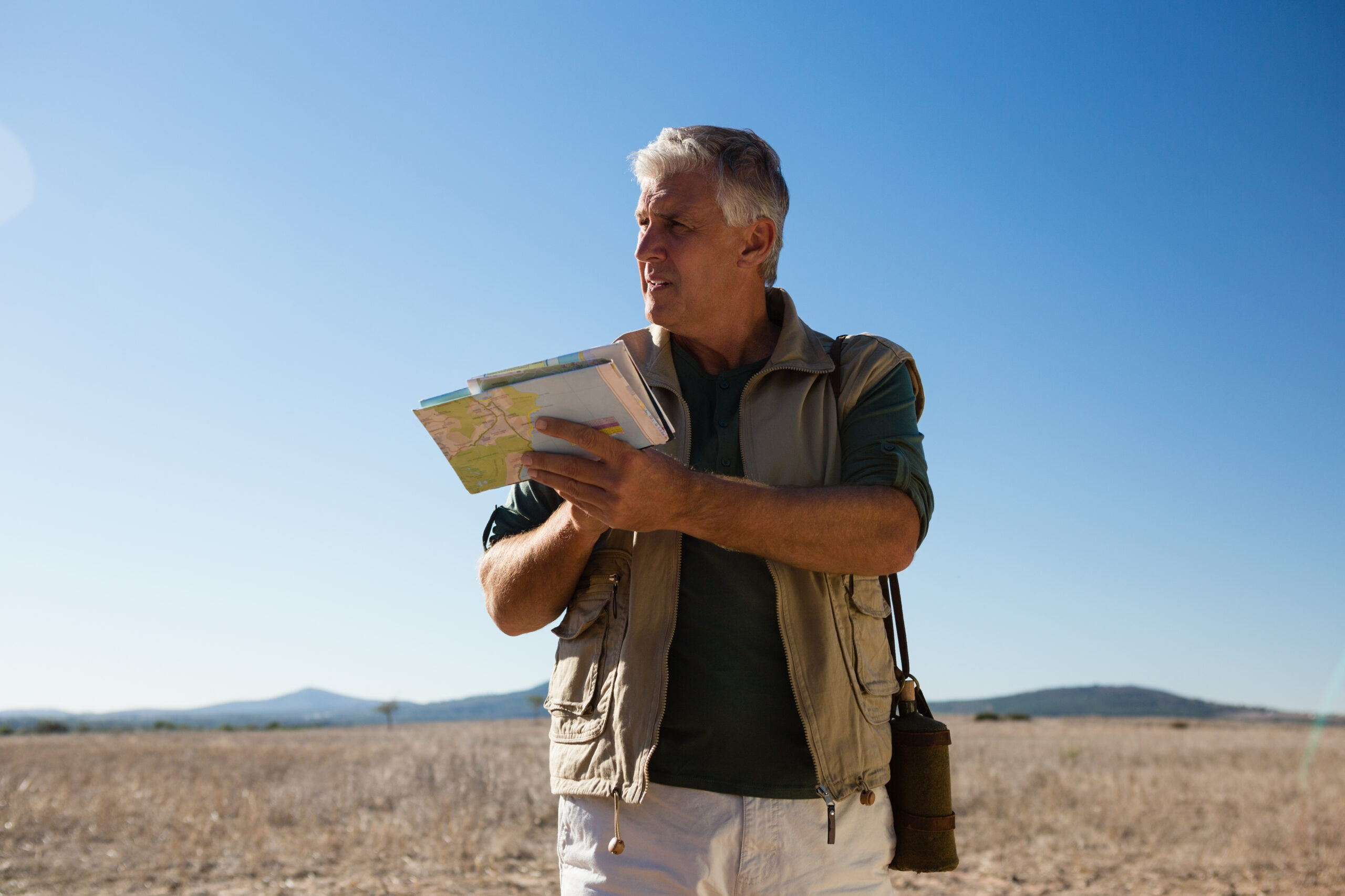 Man with map looking away while standing on landscape Steps to Start Your Slow Travel Life Today