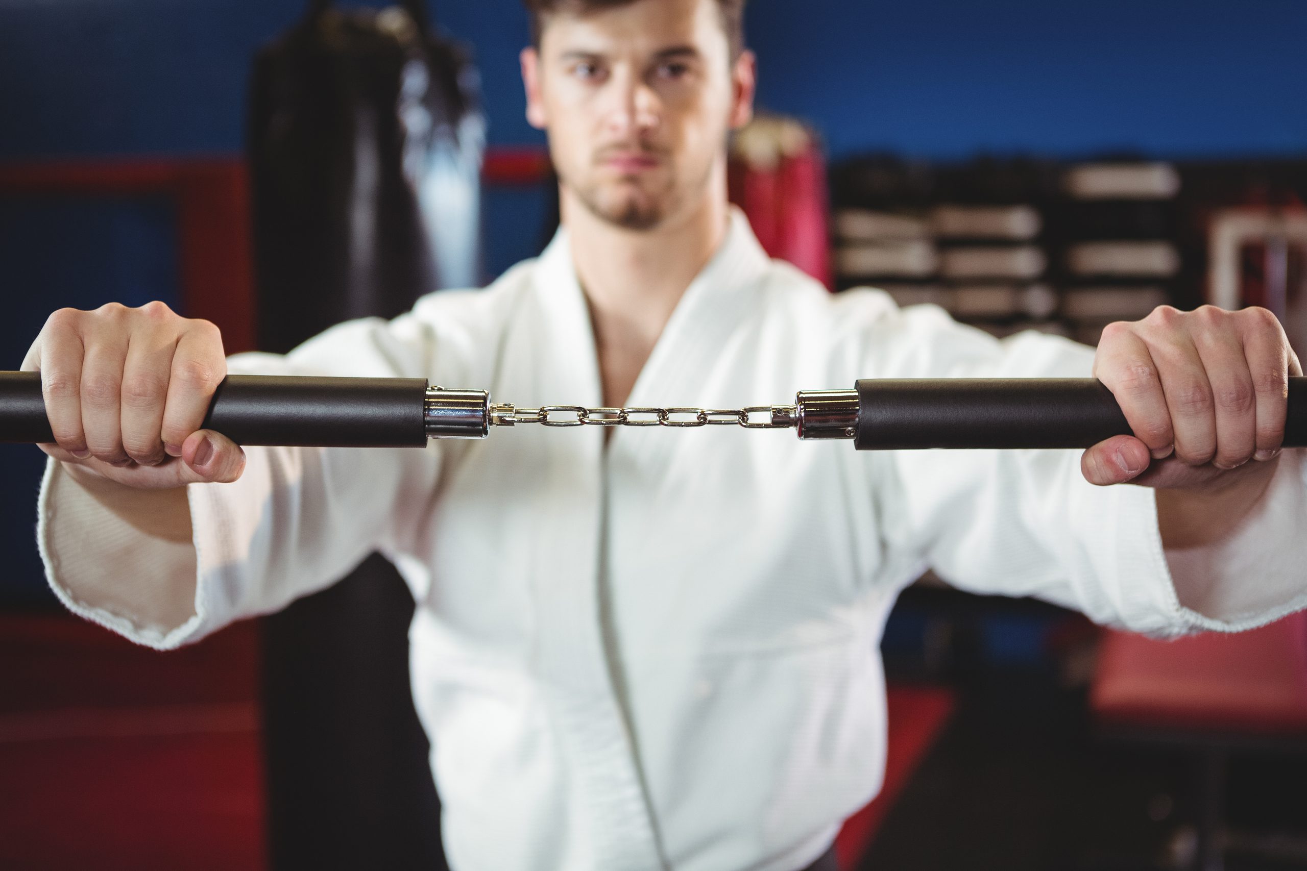 Karate player practicing with nunchaku in fitness studio